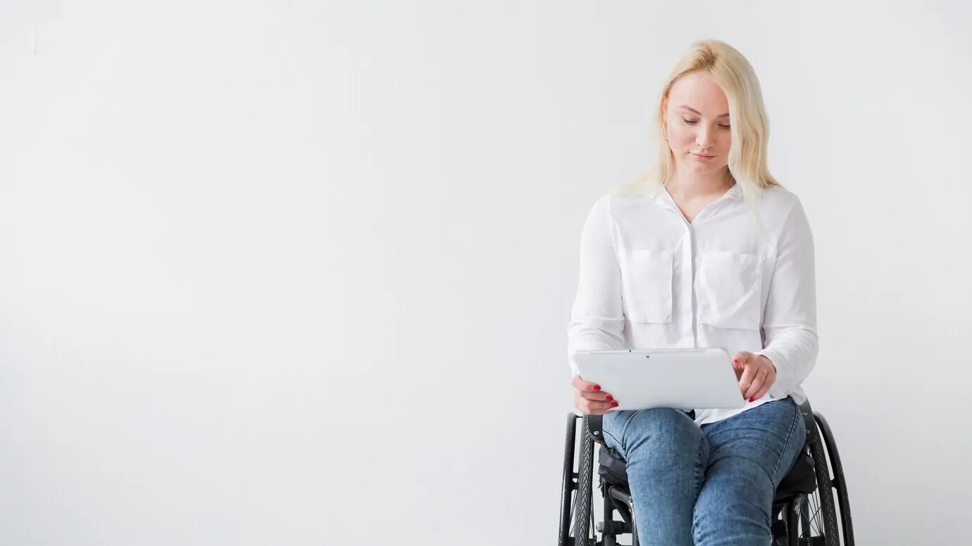 Front-facing view of a woman in a wheelchair working on a tablet.